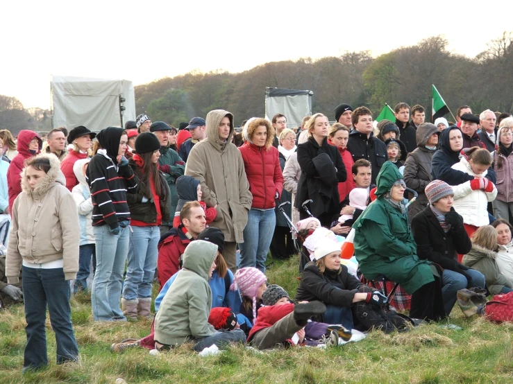 several people gathered in an open field with mountains behind them