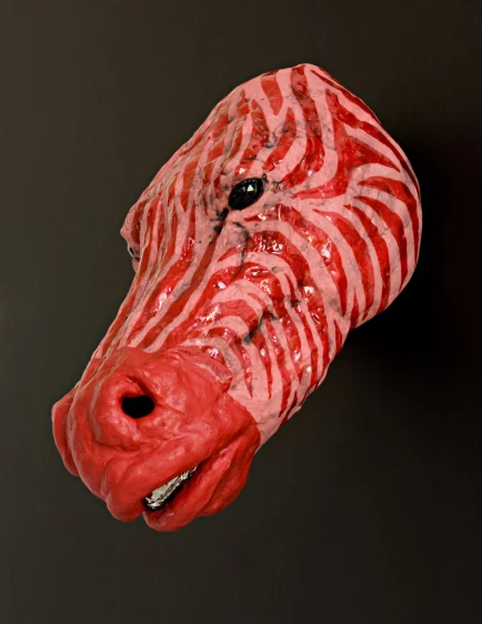 a red and white ceramic animal head, on a black background