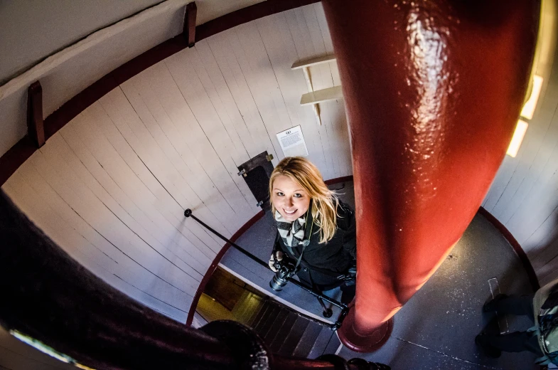 a lady is seen from the bottom floor as she looks down at her red phone