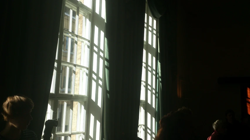 people sitting in a dark room with large windows