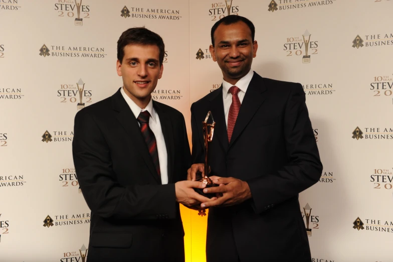 two men standing next to each other holding a trophy