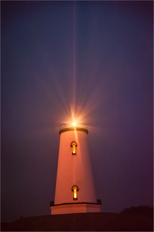 a lighthouse that is in the dark with the light shining