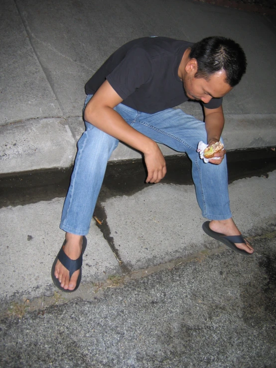 a person sitting on a step in front of a fire hydrant with food