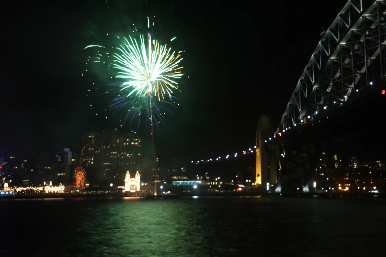 a firework show on the river next to a bridge