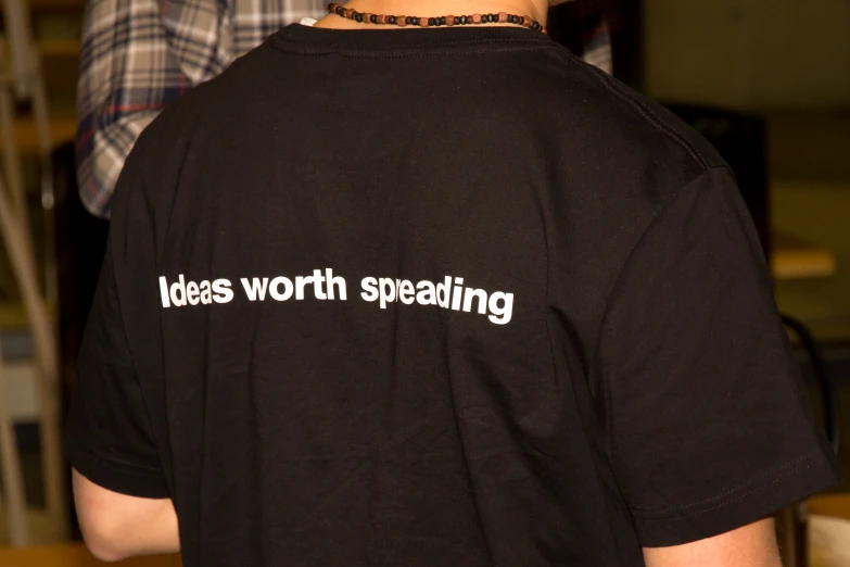 the back view of a man wearing a black shirt that reads ideas worth sweating