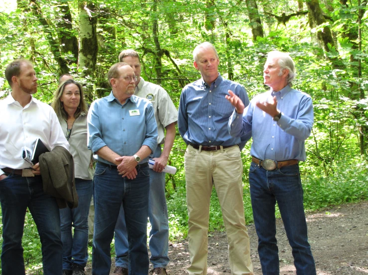 several people standing in a forest on a dirt road talking