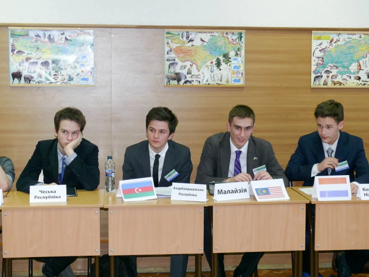 five young men sitting at the end of a long row