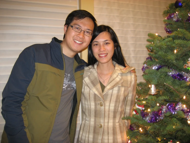 a man and a woman standing in front of a christmas tree