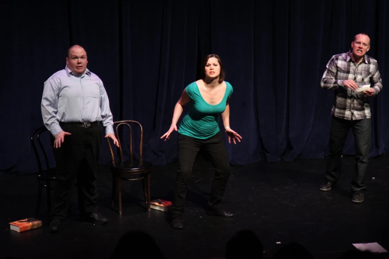 three people standing and clapping in front of a blue curtain