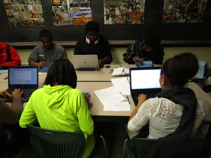 students with laptop computers are gathered around the table