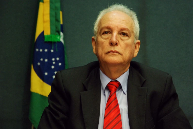 a man is sitting in front of flags in front of him