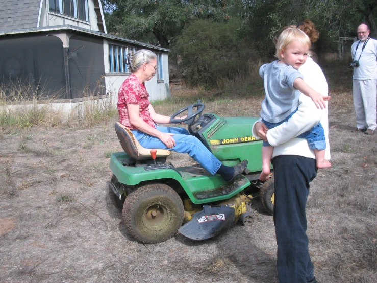 three people that are in a yard with a tractor