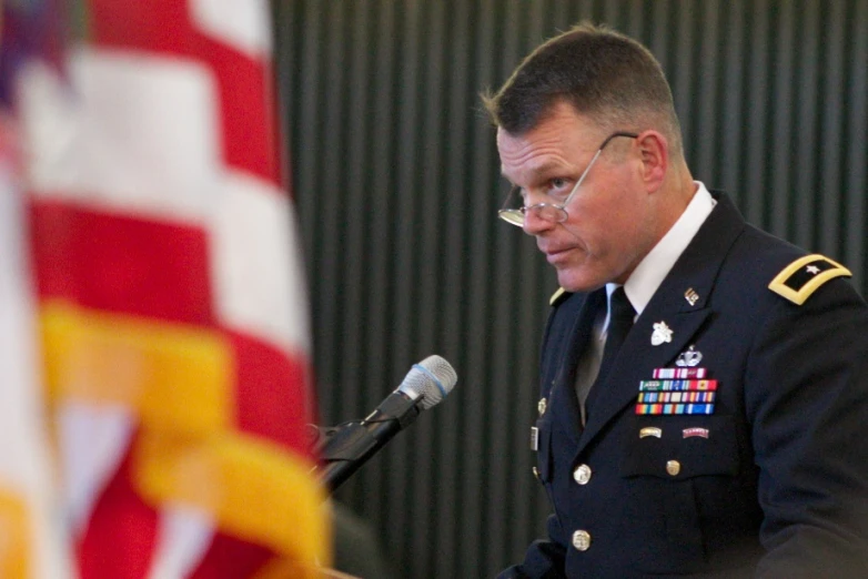 a military officer in uniform speaks from a podium