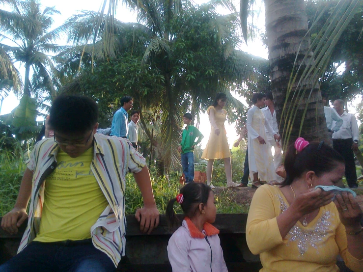 a group of people sitting on a wooden bench near trees