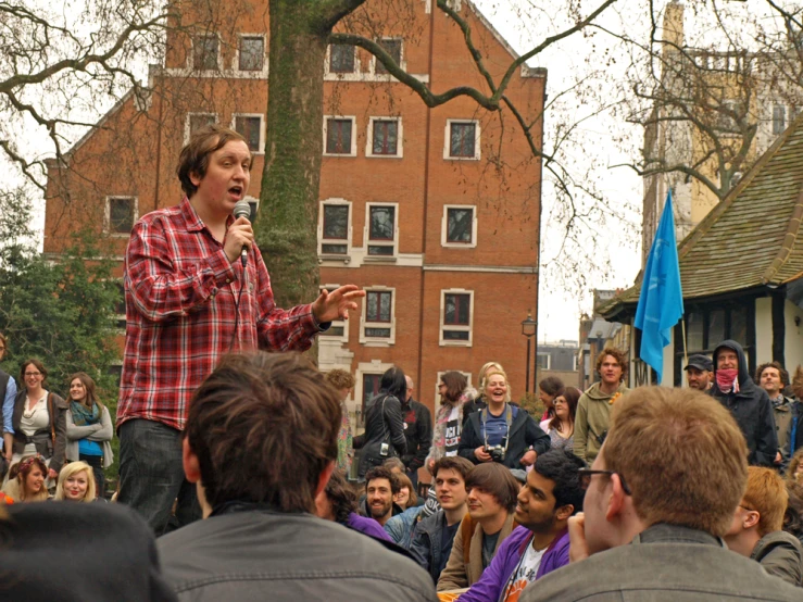 a man speaks into the microphone in front of a group of people