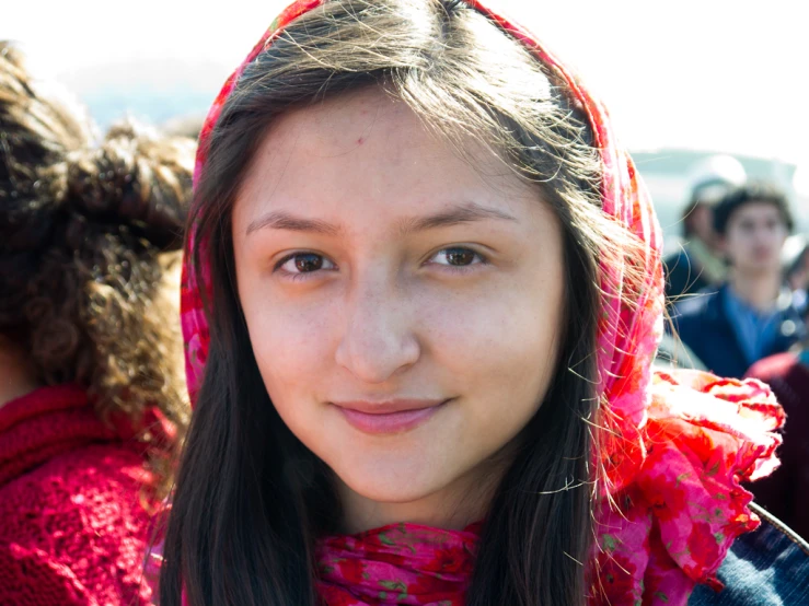 a  wearing a scarf smiles at the camera