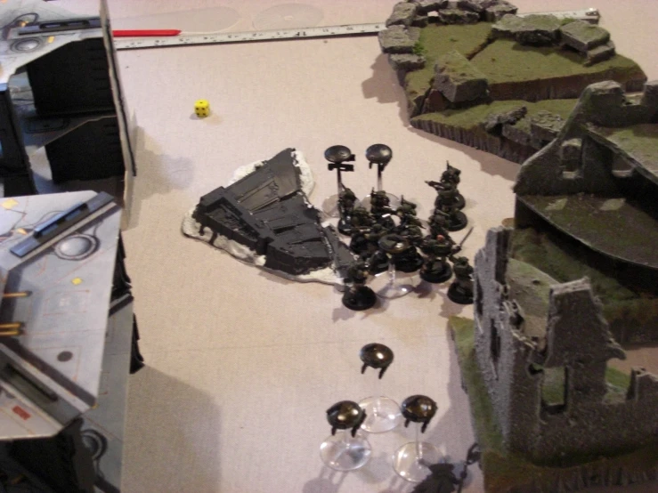 some small plastic wargame figures are in the middle of a small table