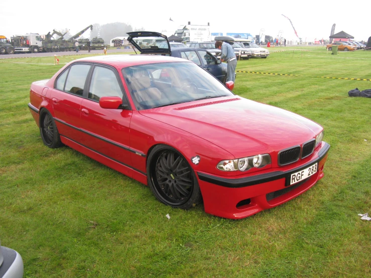 a red bmw car is parked in the grass