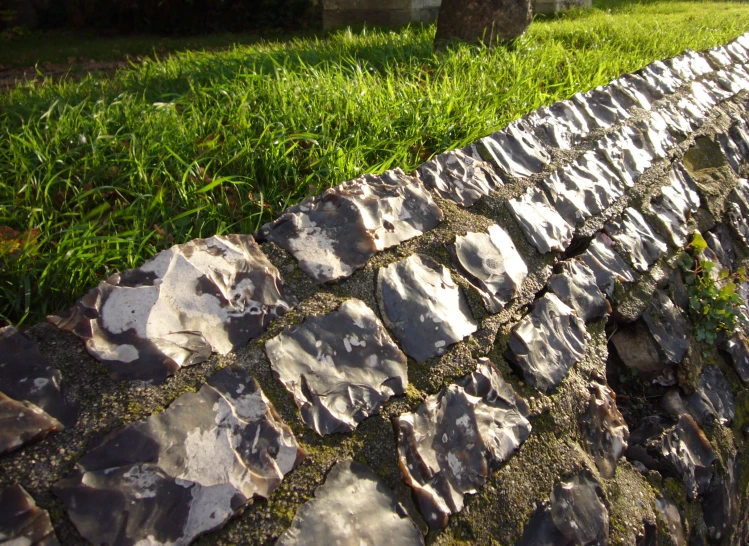 a stone wall sits in the grass next to a park