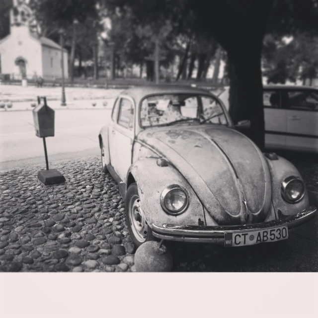 a small car parked under a tree on a street