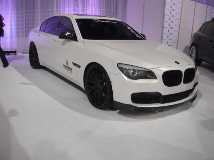 a white car that is on display next to two women