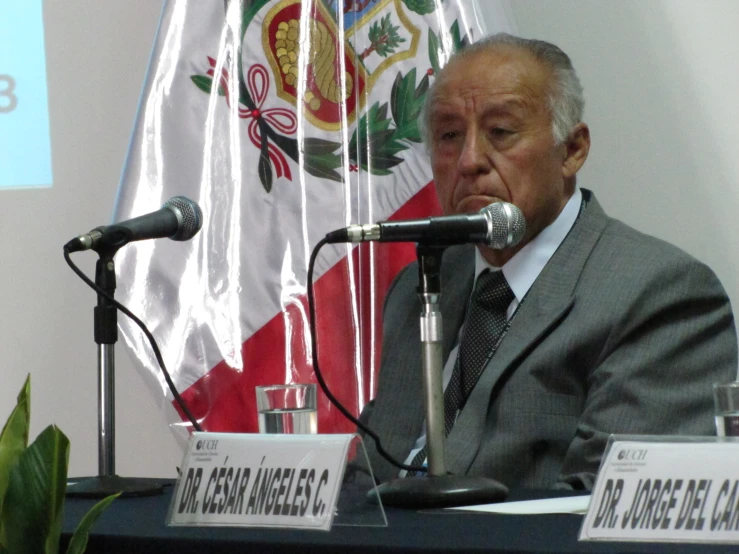 a man sits at a table with microphone in front of him