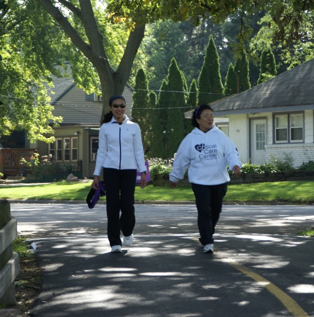 two young women walking down the street with a house behind them