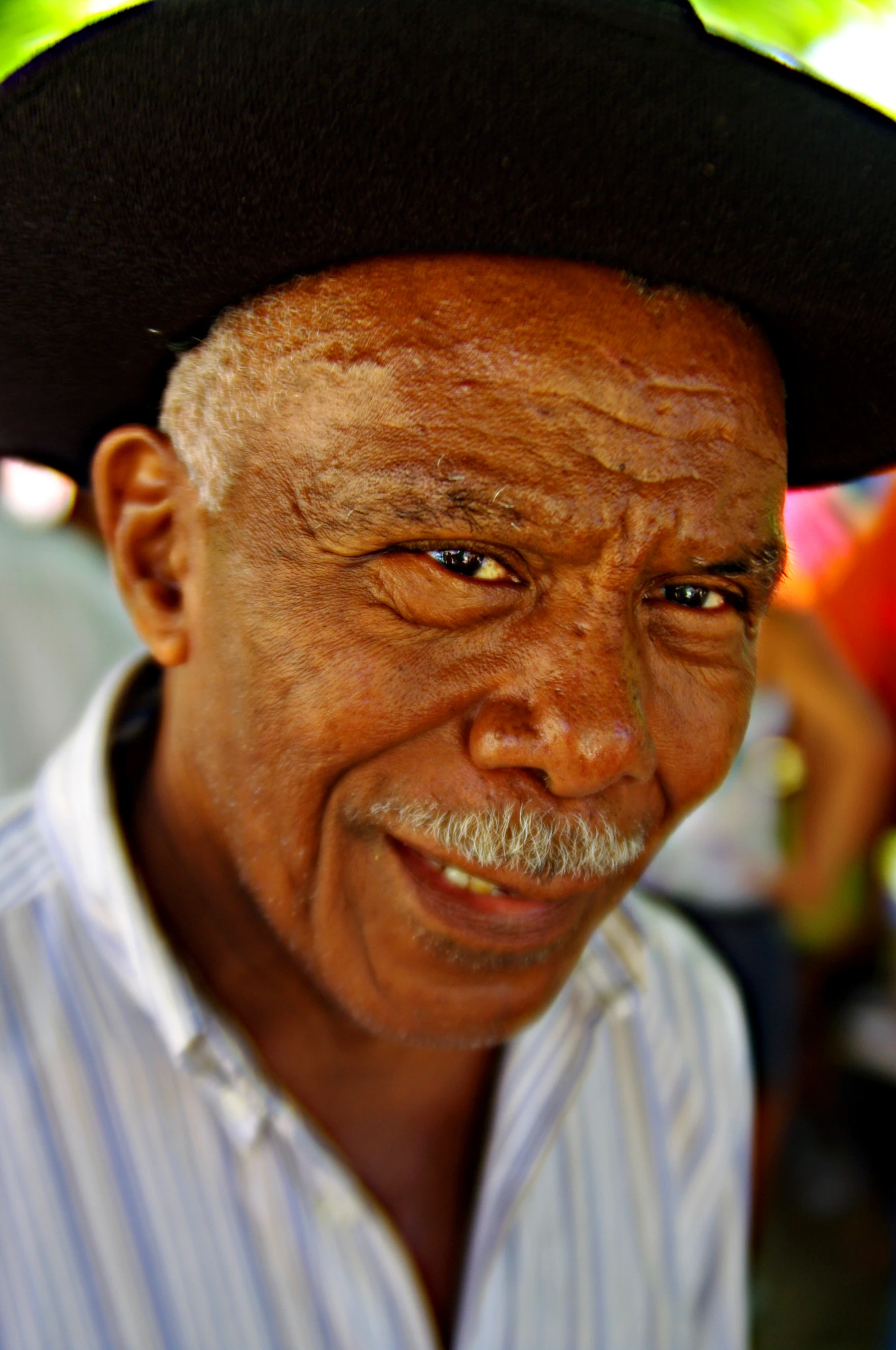 an old man is wearing a hat and has a smile on his face