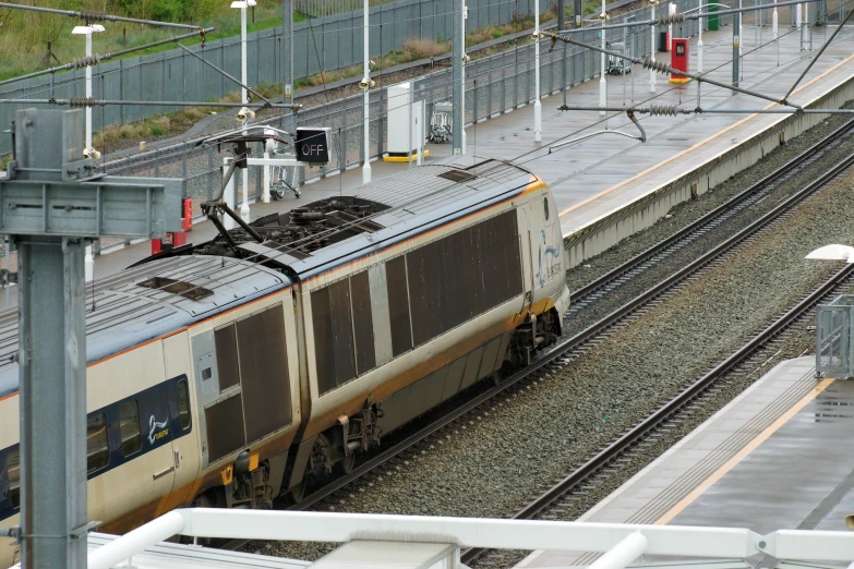 a yellow and gray train driving down tracks