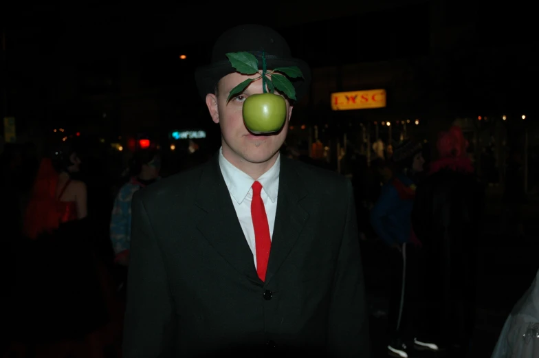 a man dressed in black with an apple on his nose