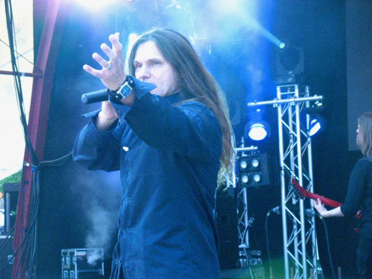 a man standing in front of a microphone with a dark suit on