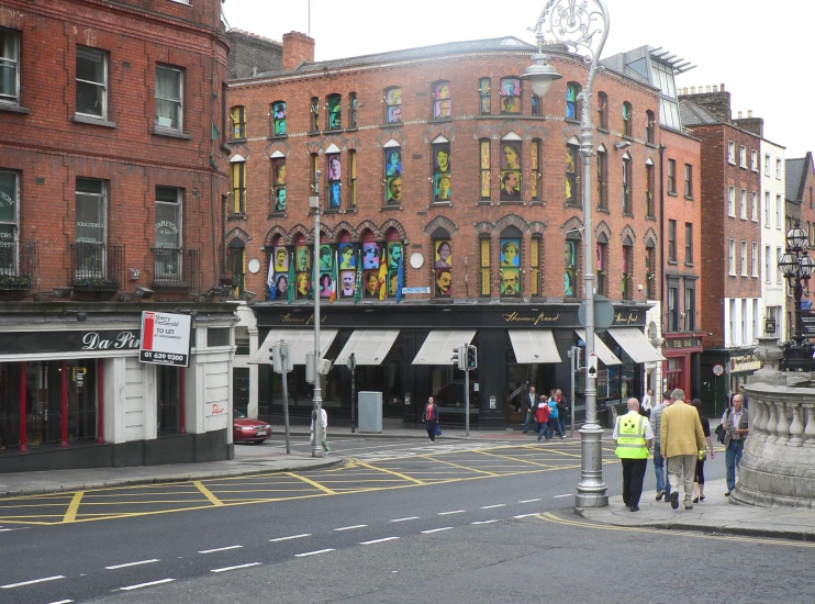 people are walking on a city street by some buildings