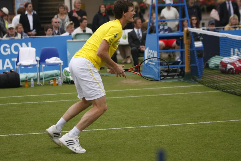 a male tennis player dressed in white and yellow swinging at a ball