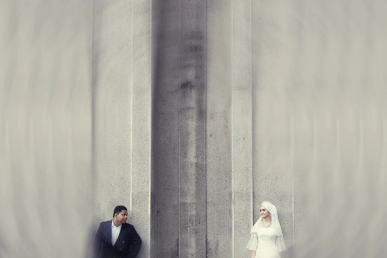 a man and a woman standing under two tall pillars