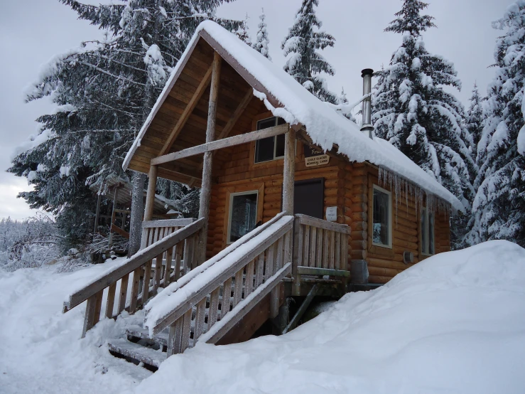 the log cabin on the hill has a snow covered porch