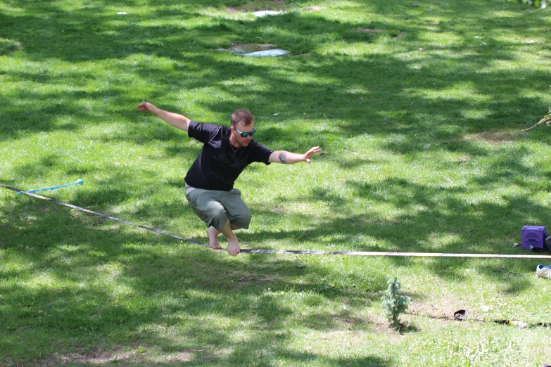 a man holding a frisbee walking on top of a lush green field