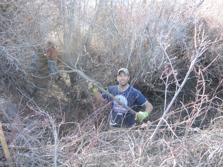 a man kneeling down in some bushes with an orange mitt