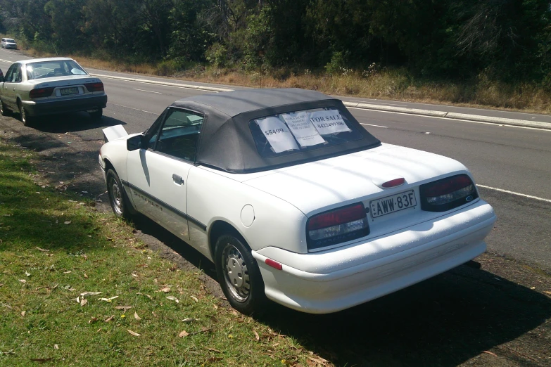 white car sitting on the side of the road with a parking meter attached to its roof