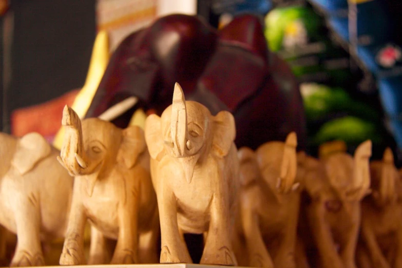 several small carved elephants on a wooden stand