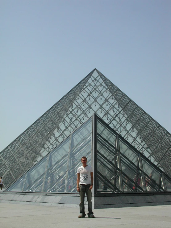 the man is standing against the large pyramid