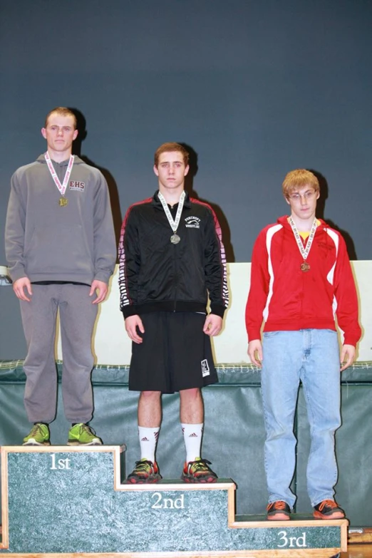 three boys are standing on a podium with medals