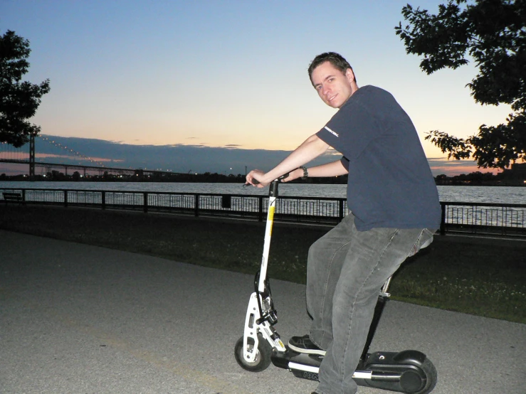 a man standing on an off - road scooter on the street