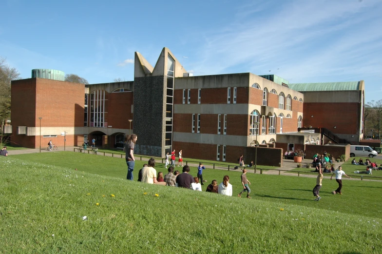 many people sit in the grass and play