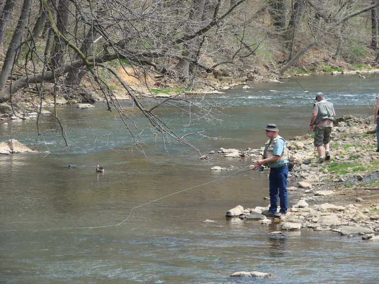 three people are walking on a rock bank while holding onto fish