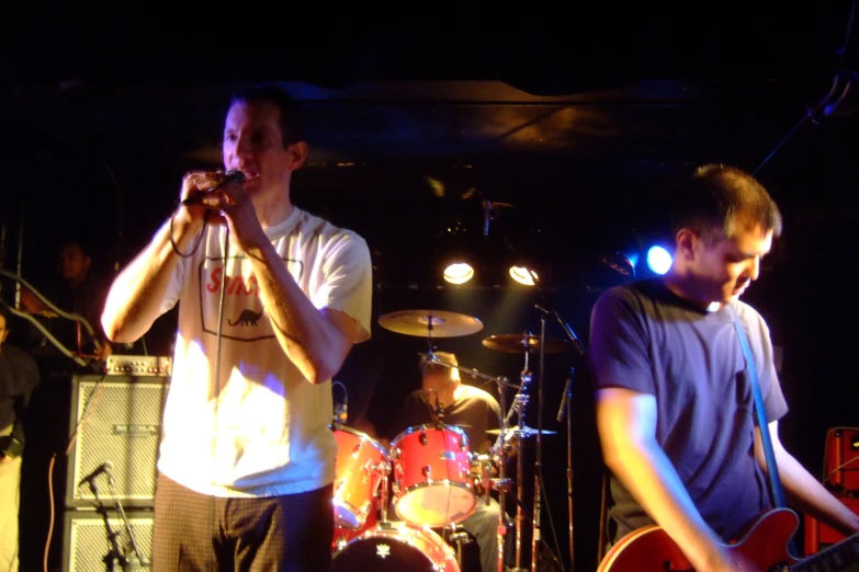 two men are standing by a concert stage singing