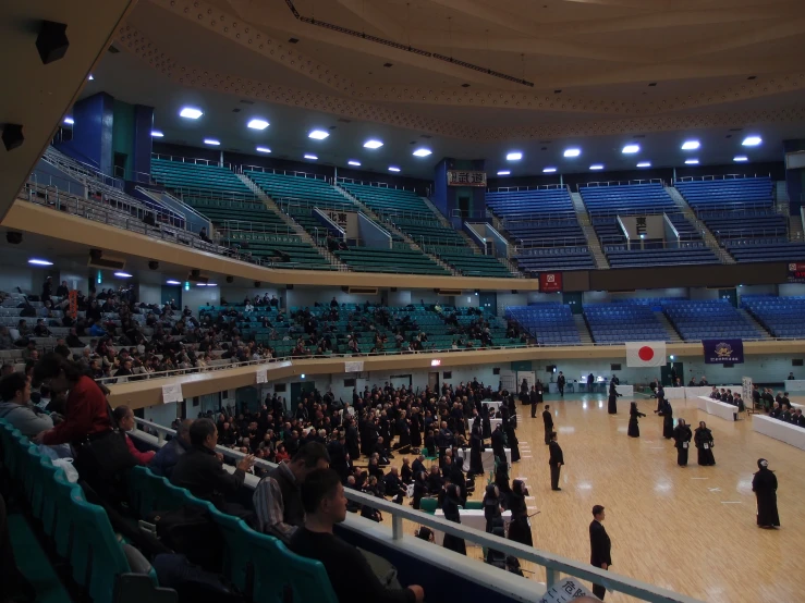 large crowd of people sitting on the floor of an arena