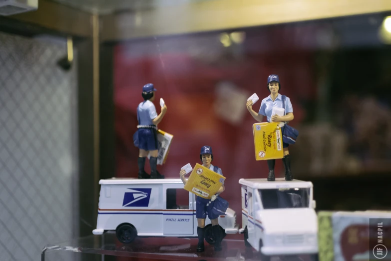 three miniature figurines on display with mailman