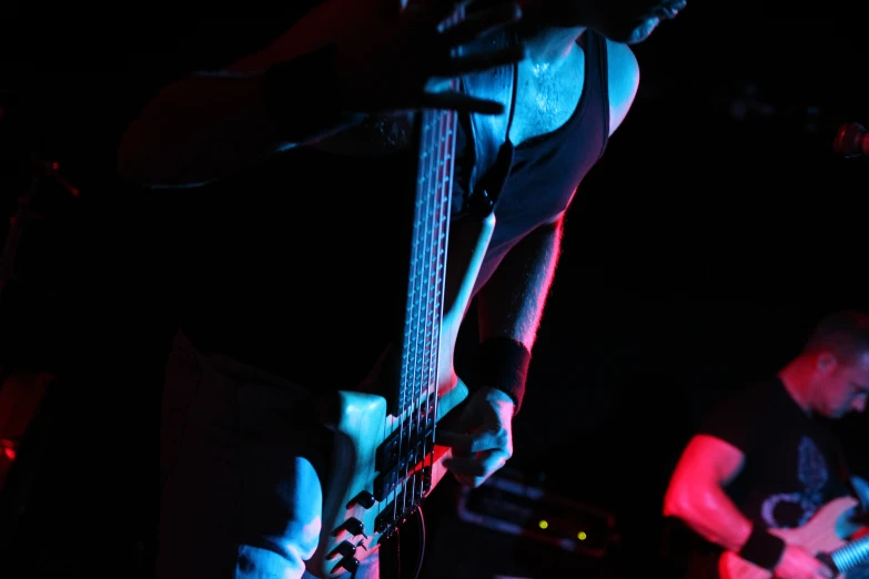 man playing guitar in dark room with blue light