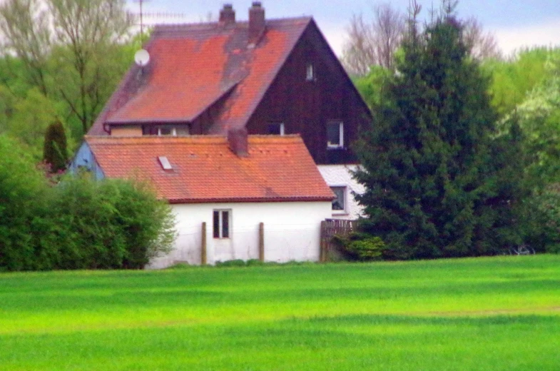 a white house is standing next to a grassy field