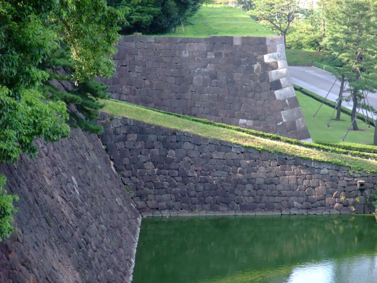 a stone wall and lake in the middle of a park